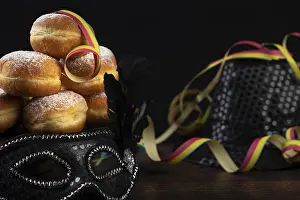 Happy Carnival Night Scene Drucke: Doughnuts against a dark background next to a black hat