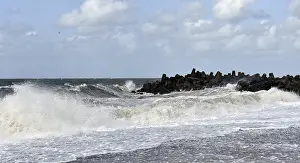 Cloudy Sky Landscape Drucke: Dramatic breakwaters hit rocks under a cloudy sky
