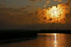 Atmospheric Evening Light Sky Drucke: Dramatic cloud formation at sunset reflected in a calm river