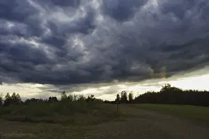 Weather Forecast Images Drucke: Dramatic, dark clouds drift across a landscape at dusk