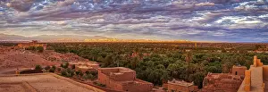 Desert Panorama Drucke: Dramatic desert panorama with oasis and mountains in the background at sunset