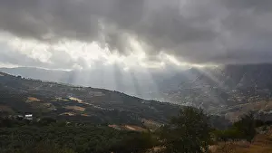 Greek Island Landscapes Drucke: Dramatic landscape with sun rays breaking through a cloud cover