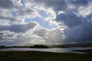 Cloudy Sky With Sun Rays Drucke: Dramatic landscape with water and sun rays through clouds in the sky
