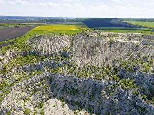 Moldova Landscape Drucke: Dramatic rock formation with erosion-shaped cliffs surrounded by green fields under clear sky