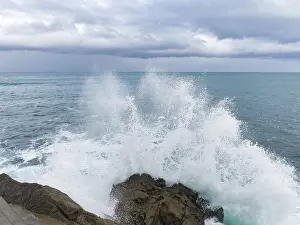 Panoramic Ocean View Drucke: A dramatic scene as powerful waves collide with rugged rocks under a brooding sky