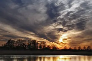 Natural Preserve In Eastern Germany Drucke: Dramatic sunset sky with trees and soft reflection in water