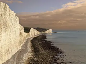 British Countryside Views Drucke: Dramatic sunset view of white cliffs and a pebbly beach along the sea