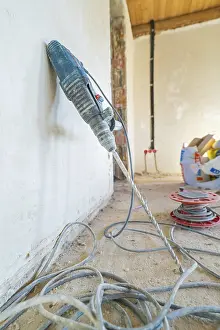 Dusty Construction Site Drucke: A drill is leaning against a dusty wall on a construction site