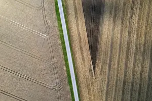 High Angle View Of Agriculture Drucke: Drone shot, road through harvested fields with abstract patterns