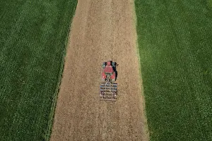 Agricultural Landscape In Austria Drucke: Drone view, tractor at work between green fields