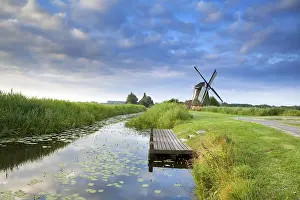 Drucke von Niederländische Windmühle am Fluss mit reflektiertem blauen Himmel, Groningen, Niederlande Groningen Drucke: Niederländische Windmühle am Fluss mit reflektiertem blauen Himmel.
