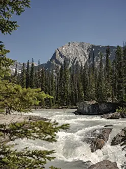 Uninhabited Natural Landmark Drucke: Dynamic river rapids cascading against rocks with a mountain