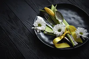 Black Wooden Background Drucke: Easter spring table dishware composition with yellow tulip flower