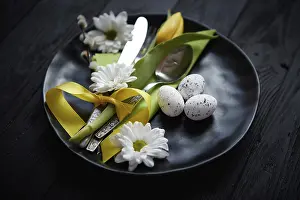 Black Wooden Background Drucke: Easter spring table dishware composition with yellow tulip flower and eggs