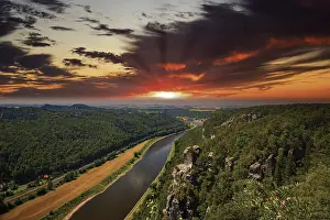 Elbe Sandstone Mountains Landscape Drucke: The Elbe meanders through a dense forest under a dramatic sunset sky