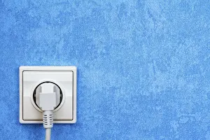 Power Supply Socket Drucke: Electrical plug connected into the socket on blue wall