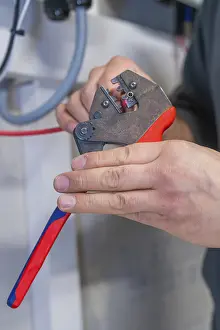 Electrician At Work Drucke: Electrician processes cables with pliers