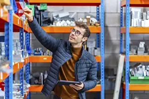 Industrial Building Architecture Drucke: Engineer using tablet in the stock room of a computer numeric control modern factory