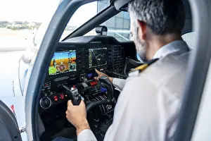 Aviation Industry Professionals Drucke: Experienced pilot wearing uniform checking navigation instruments and control panel in the cockpit of a small aircraft