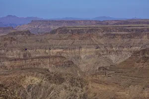 Fish River Canyon Namibia Drucke: Extensive rock formations under a blue sky over a desolate