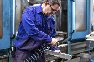 Numerical Control Sector Drucke: Factory worker operator in the numerical control sector cleaning a part with compressed air