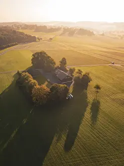 Sunset Farm Scene Drucke: A farm surrounded by fields and trees in the evening light