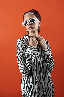 Drucke von Ein Modeschönheitsfehler posiert selbstbewusst in einem Streifenmusterbluse, die mit modernen Accessoires geschmückt ist Kräftige Farben Drucke: Ein Modeschönheit posiert selbstbewusst in einem Streifenmusterbluse.
