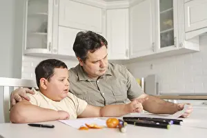 Learning Environment Drucke: A father helps his son with homework at the kitchen table