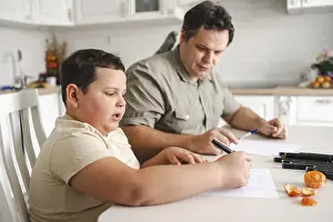Parent Child Relationship Drucke: A father and son sit together at a kitchen table drawing