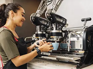 Female Barista Drucke: Female barista using a coffee machine