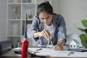 Residential Building Drucke: A female engineer in a denim jacket uses a compass for architectural drafting