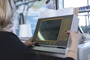 Automated Manufacturing Process Drucke: Female operator setting programme at knitting machine control panel view