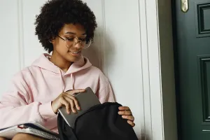 Educational Institution Images Drucke: Female student pulls out digital tablet from backpack