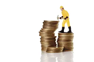 Symbolic Construction Image Drucke: Figure of a construction worker with hard hat and pickaxe on a stack of coins