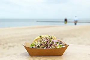 Bilder Datiert 7. Mai 2024: Fische rollen in einer Sandwichbox auf einem Tisch auf einem Strand.