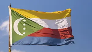 Drucke von Die Flagge der Komoren flattert im Wind, isoliert gegen einen blauen Himmel Komoren Drucke: Die Flagge der Komoren flattert im Wind.