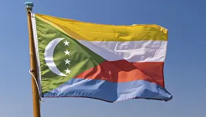 Drucke von Die Flagge der Komoren flattert im Wind, isoliert gegen einen blauen Himmel Komoren Drucke: Die Flagge der Komoren flattert im Wind.