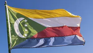 Drucke von Die Flagge der Komoren flattert im Wind, isoliert gegen einen blauen Himmel Komoren Drucke: Die Flagge der Komoren flattert im Wind.