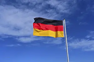 German Nationality Symbol Drucke: The flag of Germany flutters in the wind against a blue cloudless sky