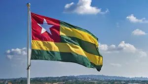 Drucke von Die Flagge Togos flattert im Wind, isoliert gegen einen blauen Himmel Togo Drucke: Die Flagge von Togo flattert im Wind.