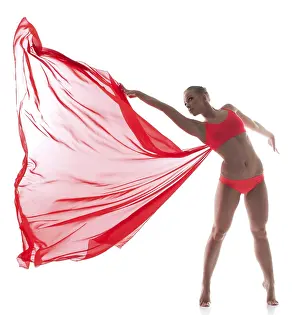 Young Woman Dance Pose Drucke: Flexible dancer posing with red cloth in studio