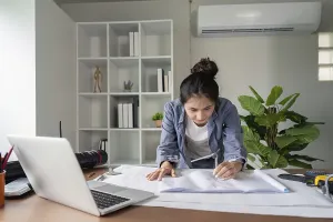 Modern Office Space Drucke: A focused engineer analyzes blueprints at her desk