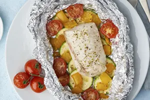 Drucke von Foliepack-Dinner mit weißem Fisch. Backofen gebratener Fillet aus Kabeljau, Hecht mit Gemüse und Pesto-Sauce. Gesunde Ernährung, Keto-Diät, mediterranes Kochbuch. Blauer Hintergrund Kabeljau Drucke: Fisch im Folienbeutel.