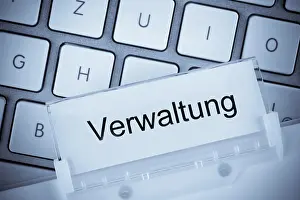 Construction Industry Drucke: The folder of a hanging file in front of a computer keyboard on the subject of administration