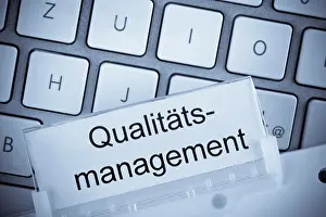 Computer Keyboard Image Drucke: The folder of a hanging file in front of a computer keyboard on the subject of quality management