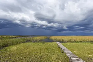 Dramatic Sky Photography Drucke: Footbridge at the lakeside with dramatic sky
