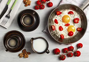 Breakfast On A Wooden Table Drucke: Two fried eggs with cherry tomatoes in a pan