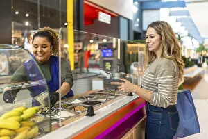 Healthy Grocery Options Drucke: Friendly server preparing a custom dessert for a smiling customer selecting various toppings from a display at a