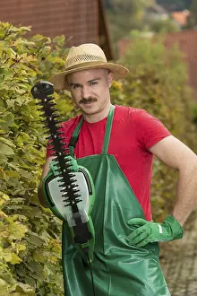 Caucasian Man Gardening Drucke: Gardener using a hedge trimmer