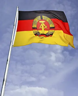 German Democratic Republic Flag Drucke: GDR flag on flagpole in front of a cloudy sky